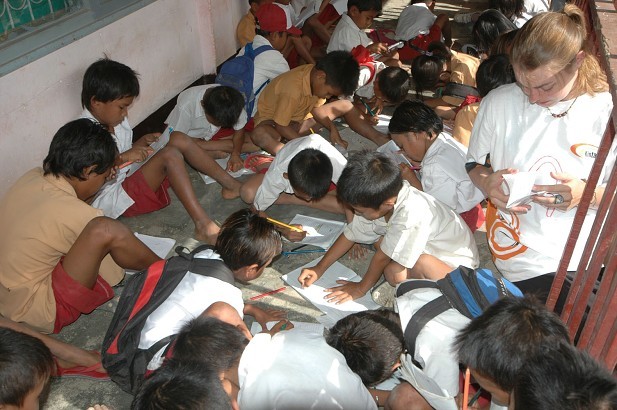 Děti se učí na betonu před školou, Ngolang, Indonésie