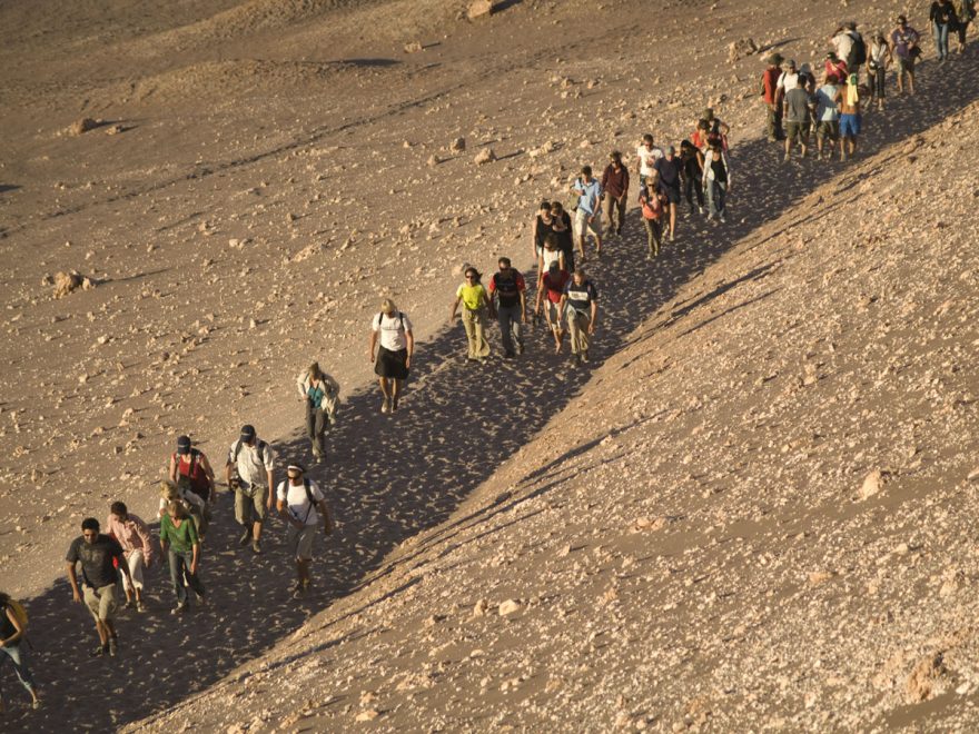 Zástup lidí kráčí na západ slunce v Měsíčním údolí v Chile