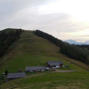Travnaté sedlo mezi Faistenauer Schafberg a Loibersbacher Höhe s několika typickými lučními chaloupkami (Almhütte). Rakousko