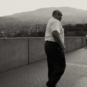 Most přes městkou stoku v Medelínu s pozadím chudinské a dodnes nebezpečné čtvrti Araunjuez