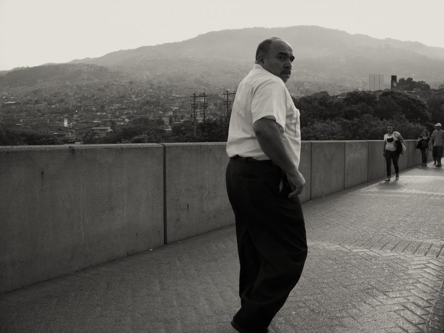 Most přes městkou stoku v Medelínu s pozadím chudinské a dodnes nebezpečné čtvrti Araunjuez