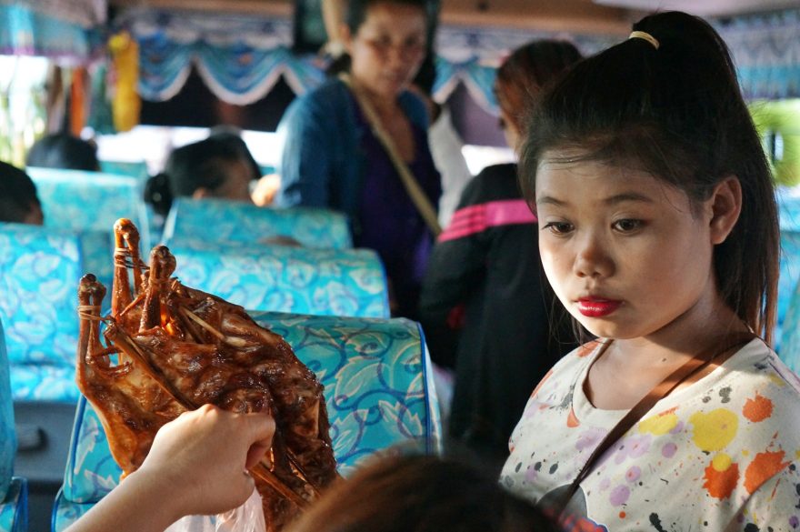 Prodej občerstvení v autobuse – kuře na špejli kai yang, Laos
