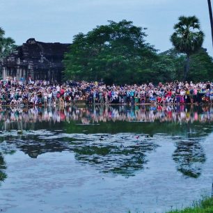 Turisté před Angkor Watem fotí zrcadlení chrámu při východu slunce. Dav se také zrcadlí…